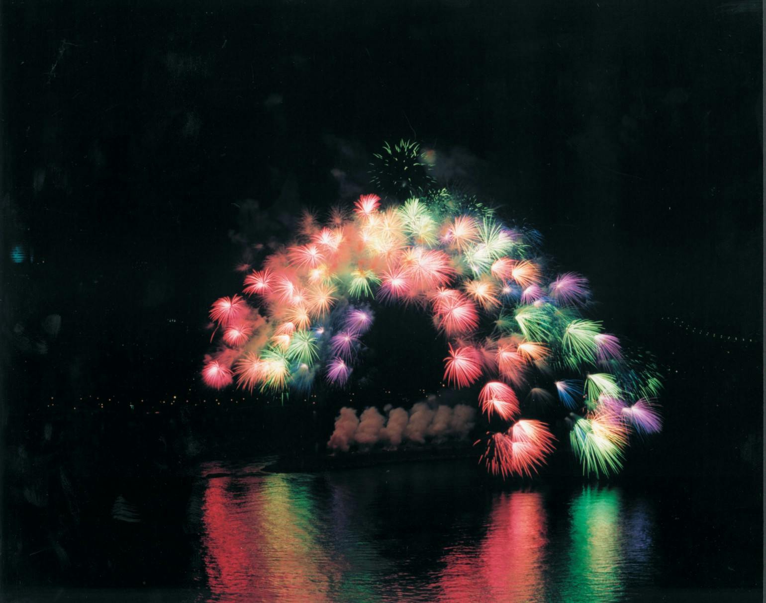 蔡国强，《移动彩虹》，2002。于纽约的东河上实施、从曼哈顿到皇后区，纽约， 6月29日，晚上9:30分, 历时15秒钟。1000枚3英吋大小、安装了电脑芯片的彩色牡丹花型焰火，爆破半径约200米