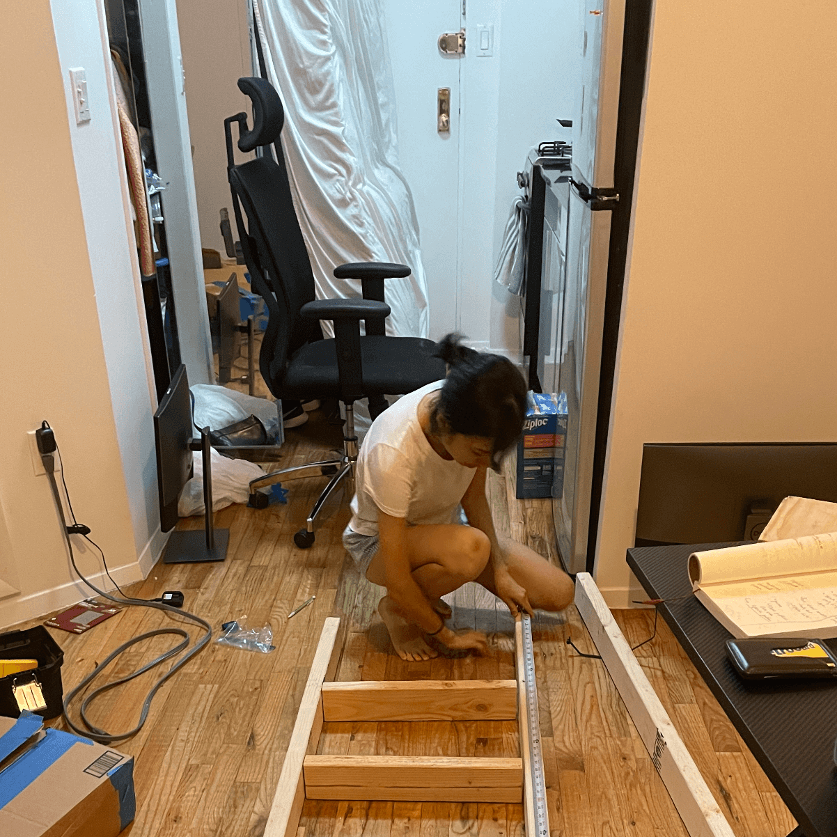 My roommate Cat arranged where we wanted the rungs to be on the ladder. In the background, you can see that during construction, we pushed my mattress, desk, and monitors to rest in the apartment doorway. 
