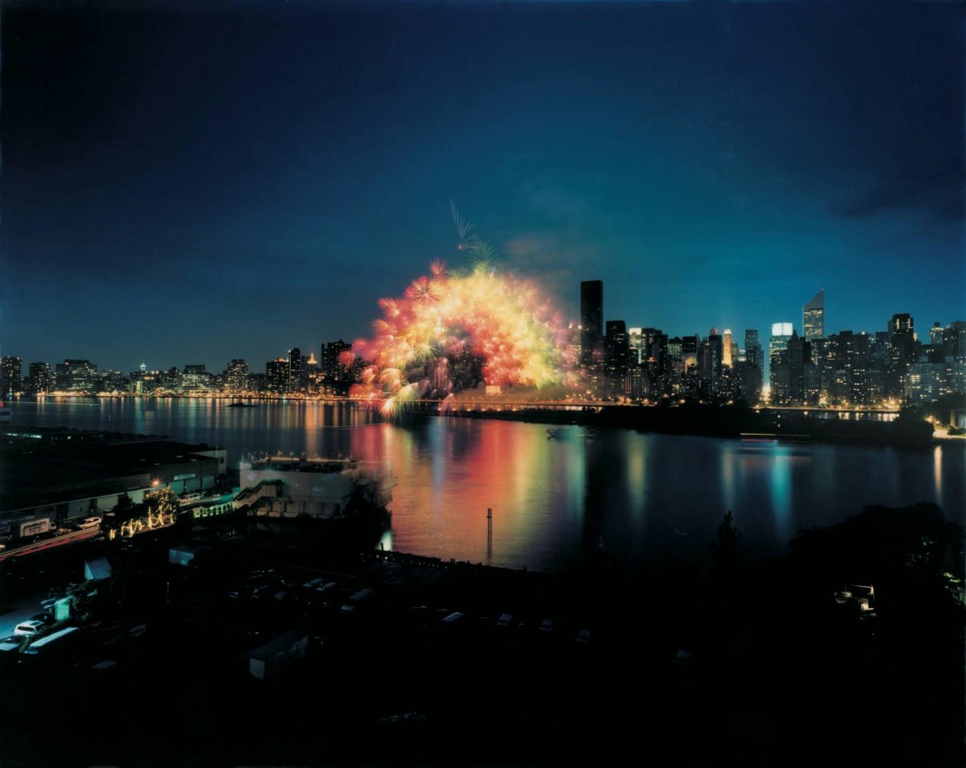 蔡国强，《移动彩虹》，2002。于纽约的东河上实施、从曼哈顿到皇后区，纽约， 6月29日，晚上9:30分, 历时15秒钟。1000枚3英吋大小、安装了电脑芯片的彩色牡丹花型焰火，爆破半径约200米